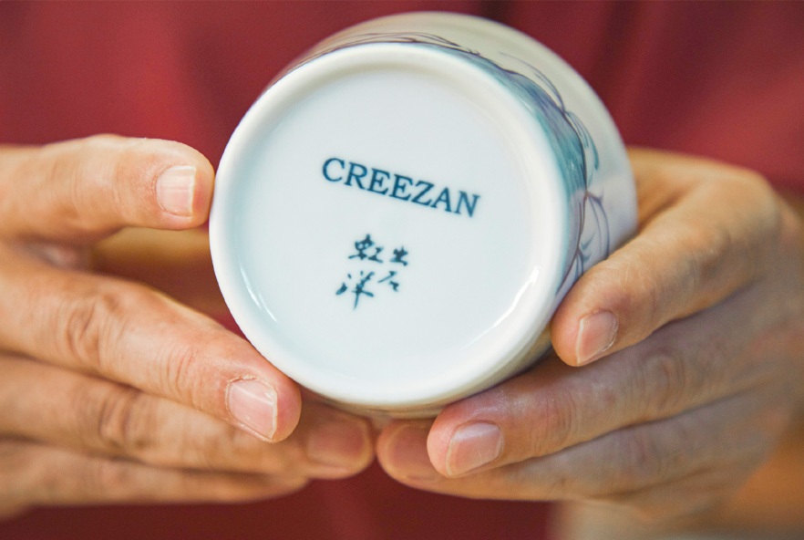11　豊岡のバッグブランド「CREEZAN」とのダブルネームが記されたそば猪口。「CREEZAN」製のレザーバンドを装着すると、マグカップのように使える仕様になっている。