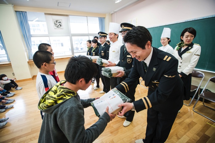 松江市立宍道小学校の児童に記念ノベルティーを贈る「瑞風」クルーたち